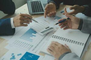 Group of confident business people point to graphs and charts to analyze market data, balance sheet, account, net profit to plan new sales strategies to increase production capacity. photo
