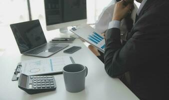 Group of confident business people point to graphs and charts to analyze market data, balance sheet, account, net profit to plan new sales strategies to increase production capacity. photo