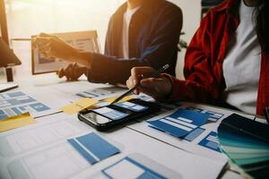 Close up ux developer and ui designer brainstorming about mobile app interface wireframe design on table with customer breif and color code at modern office.Creative digital development agency photo