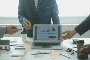 Group of confident business people point to graphs and charts to analyze market data, balance sheet, account, net profit to plan new sales strategies to increase production capacity. photo