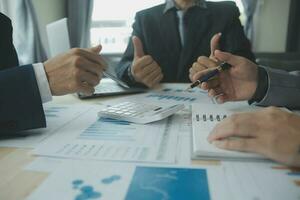 Group of confident business people point to graphs and charts to analyze market data, balance sheet, account, net profit to plan new sales strategies to increase production capacity. photo