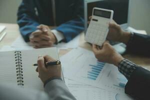 Group of confident business people point to graphs and charts to analyze market data, balance sheet, account, net profit to plan new sales strategies to increase production capacity. photo