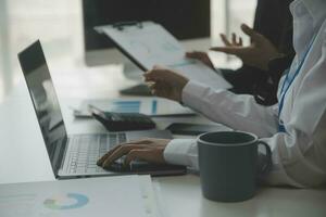 Group of confident business people point to graphs and charts to analyze market data, balance sheet, account, net profit to plan new sales strategies to increase production capacity. photo