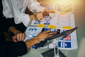 Close up ux developer and ui designer brainstorming about mobile app interface wireframe design on table with customer breif and color code at modern office.Creative digital development agency photo