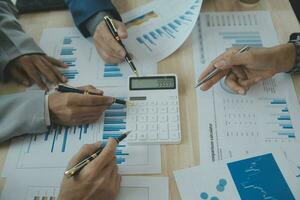 Group of confident business people point to graphs and charts to analyze market data, balance sheet, account, net profit to plan new sales strategies to increase production capacity. photo