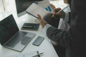 Group of confident business people point to graphs and charts to analyze market data, balance sheet, account, net profit to plan new sales strategies to increase production capacity. photo
