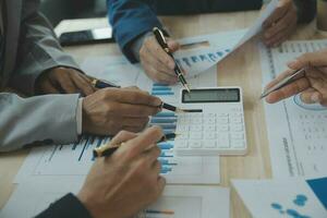 Group of confident business people point to graphs and charts to analyze market data, balance sheet, account, net profit to plan new sales strategies to increase production capacity. photo