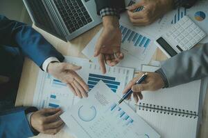 Group of confident business people point to graphs and charts to analyze market data, balance sheet, account, net profit to plan new sales strategies to increase production capacity. photo