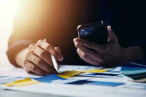 Close up ux developer and ui designer brainstorming about mobile app interface wireframe design on table with customer breif and color code at modern office.Creative digital development agency photo
