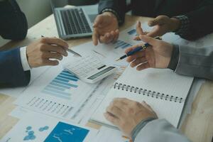 Group of confident business people point to graphs and charts to analyze market data, balance sheet, account, net profit to plan new sales strategies to increase production capacity. photo
