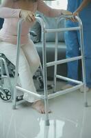 young asian physical therapist working with senior woman on walking with a walker photo