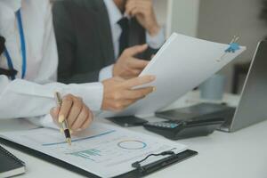 Group of confident business people point to graphs and charts to analyze market data, balance sheet, account, net profit to plan new sales strategies to increase production capacity. photo