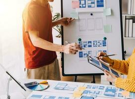 Close up ux developer and ui designer brainstorming about mobile app interface wireframe design on table with customer breif and color code at modern office.Creative digital development agency photo