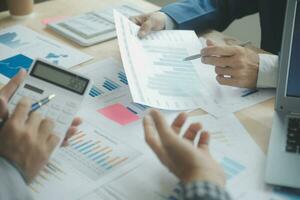 Group of confident business people point to graphs and charts to analyze market data, balance sheet, account, net profit to plan new sales strategies to increase production capacity. photo