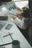 Group of confident business people point to graphs and charts to analyze market data, balance sheet, account, net profit to plan new sales strategies to increase production capacity. photo