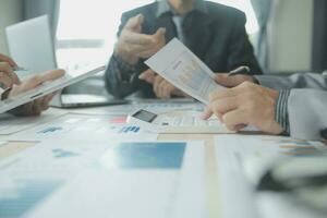 Group of confident business people point to graphs and charts to analyze market data, balance sheet, account, net profit to plan new sales strategies to increase production capacity. photo