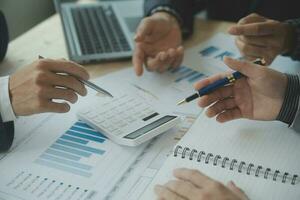 Group of confident business people point to graphs and charts to analyze market data, balance sheet, account, net profit to plan new sales strategies to increase production capacity. photo