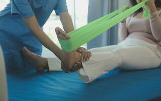 young asian physical therapist working with senior woman on walking with a walker photo