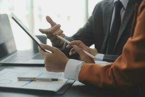 Group of confident business people point to graphs and charts to analyze market data, balance sheet, account, net profit to plan new sales strategies to increase production capacity. photo
