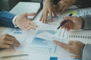 Group of confident business people point to graphs and charts to analyze market data, balance sheet, account, net profit to plan new sales strategies to increase production capacity. photo