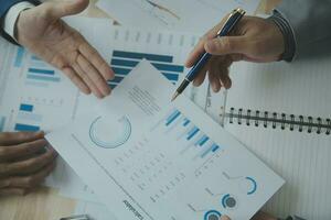 Group of confident business people point to graphs and charts to analyze market data, balance sheet, account, net profit to plan new sales strategies to increase production capacity. photo