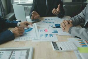 Group of confident business people point to graphs and charts to analyze market data, balance sheet, account, net profit to plan new sales strategies to increase production capacity. photo