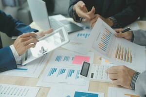 Group of confident business people point to graphs and charts to analyze market data, balance sheet, account, net profit to plan new sales strategies to increase production capacity. photo