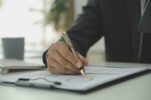 Group of confident business people point to graphs and charts to analyze market data, balance sheet, account, net profit to plan new sales strategies to increase production capacity. photo