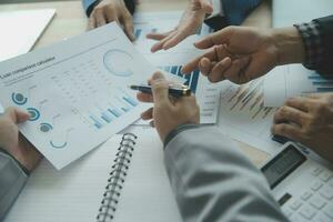 Group of confident business people point to graphs and charts to analyze market data, balance sheet, account, net profit to plan new sales strategies to increase production capacity. photo