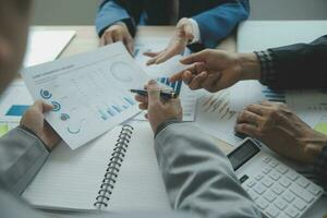 Group of confident business people point to graphs and charts to analyze market data, balance sheet, account, net profit to plan new sales strategies to increase production capacity. photo