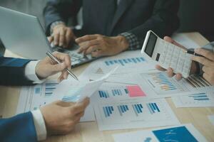 Group of confident business people point to graphs and charts to analyze market data, balance sheet, account, net profit to plan new sales strategies to increase production capacity. photo