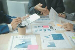 Group of confident business people point to graphs and charts to analyze market data, balance sheet, account, net profit to plan new sales strategies to increase production capacity. photo