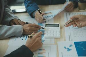 Group of confident business people point to graphs and charts to analyze market data, balance sheet, account, net profit to plan new sales strategies to increase production capacity. photo