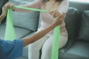 young asian physical therapist working with senior woman on walking with a walker photo