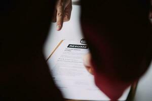 Businessman or job seeker review his resume on his desk before send to finding a new job with pen, necktie, glasses and digital tablet. photo