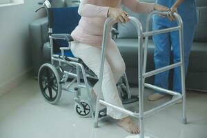 young asian physical therapist working with senior woman on walking with a walker photo