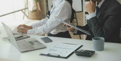 Group of confident business people point to graphs and charts to analyze market data, balance sheet, account, net profit to plan new sales strategies to increase production capacity. photo