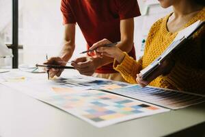 Close up ux developer and ui designer brainstorming about mobile app interface wireframe design on table with customer breif and color code at modern office.Creative digital development agency photo