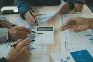 Group of confident business people point to graphs and charts to analyze market data, balance sheet, account, net profit to plan new sales strategies to increase production capacity. photo