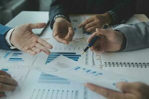 Group of confident business people point to graphs and charts to analyze market data, balance sheet, account, net profit to plan new sales strategies to increase production capacity. photo