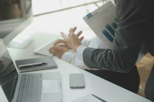 Group of confident business people point to graphs and charts to analyze market data, balance sheet, account, net profit to plan new sales strategies to increase production capacity. photo