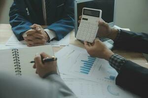 Group of confident business people point to graphs and charts to analyze market data, balance sheet, account, net profit to plan new sales strategies to increase production capacity. photo