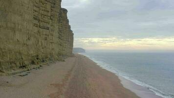 West Bay Beach With Tall Sandstone Cliffs Next the Sea in England video