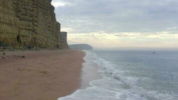 West Bay Beach With Tall Sandstone Cliffs Next the Sea in England video
