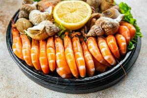 fresh seafood plate snack shrimp, crab claw, clam, rapan, trumpeter mollusk  meal food on the table copy space food background rustic top view photo