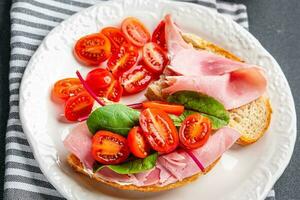 Bruschetta jamón emparedado tomate, lechuga bocadillo comida comida bocadillo en el mesa Copiar espacio comida antecedentes rústico parte superior ver foto