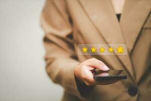 Customer pressing satisfaction with gold five star rating feedback icon and press level excellent rank for giving best score point to review the service , experience success business rate  concept. photo