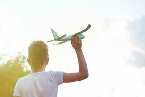 Happy child boy playing with toy airplane outdoor at sunset photo