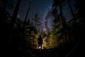 man looks at the starry sky in the forest photo