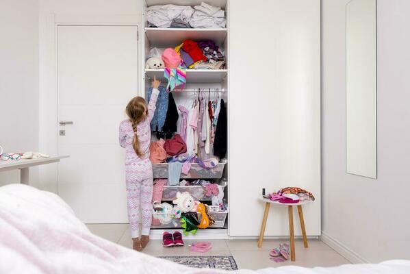 pequeño niña en rosado rosado pijama cuelga cosas en el armario, lío en el  habitación 23458794 Foto de stock en Vecteezy